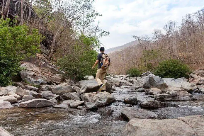 Hiker crossing river stones